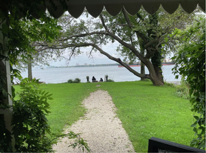 The view from a porch overlooking a gravel path that leads to the river.