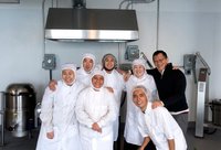Group of employees wearing chef aprons and hair nets.