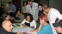 Group of people sitting and standing around a table looking at a map